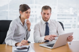 Business people working together on laptop in office at desk