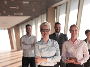 business people group standing together as team by window in modern bright office interior