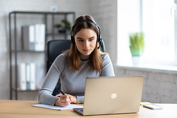 Woman watching webinar taking notes