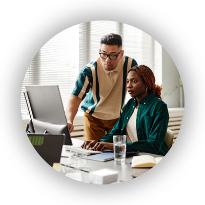 Two young workers - one male and one female - looking at a computer monitor