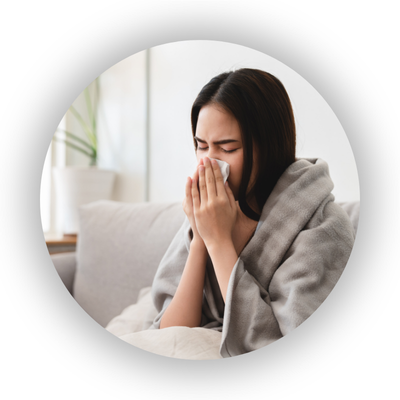 Ill woman blowing nose and wrapped in a blanket