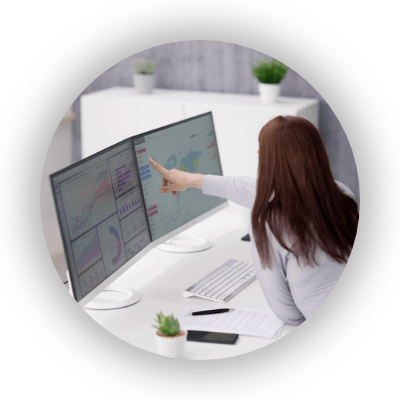 Female professional pointing at data and spreadsheets on monitors